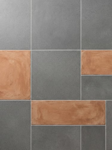 Straight-on architectural flat lay of large-format vitrified tile slabs in matte gray and terracotta clay tones, bright natural daylight, sharp focus