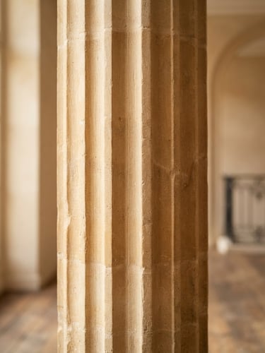 Elegant close-up of a limestone architectural column and soft sunlight casting shadows, warm neutral tones, sophisticated luxury, shallow depth of field