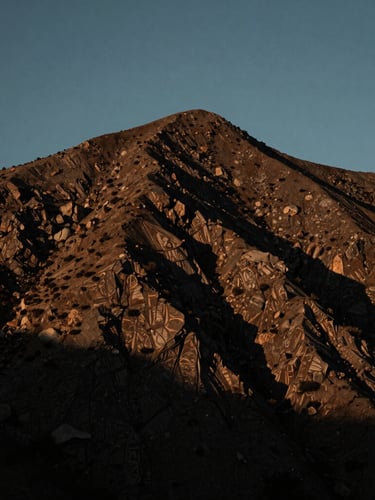A vertical portrait of a rugged mountain peak on the California Central Coast during the blue hour, low-key cinematic lighting, high-contrast shadows.