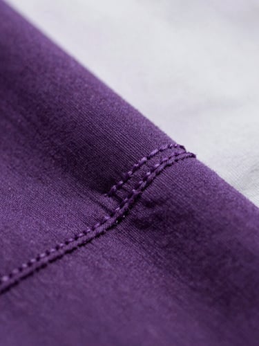 Macro close-up shot of thick 240gsm cotton fabric texture, soft overcast daylight, focus on tight double-needle stitching, deep purple and white tones