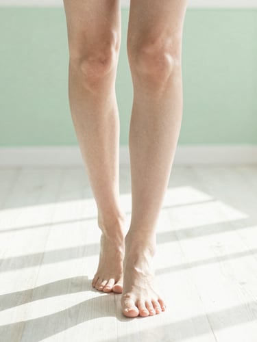 Bright editorial photography, natural morning daylight, close up of healthy legs walking on a clean sunlit wooden floor, soft green tones, shallow depth of field