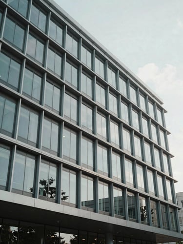 Modern corporate building facade in Wilmington, clean architectural lines of steel and glass, bright neutral daylight, cool tones, wide angle.