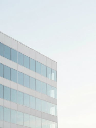 Minimalist architectural detail of a modern Orlando office building, soft morning daylight, high-key pastel sky blue reflections, clean composition with generous negative space.