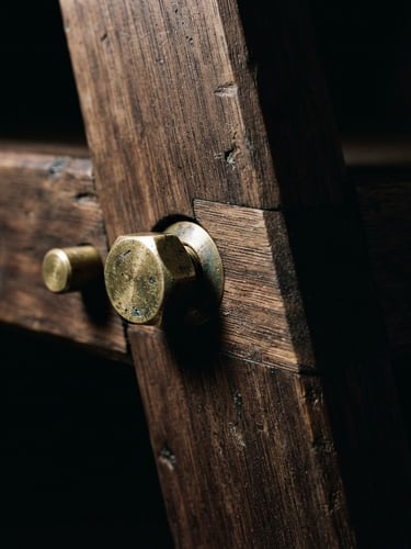 Extreme close-up macro shot of a furniture joint, raw unlacquered brass and dark oak, stark directional lighting, deep shadows, high contrast, 35mm, sculptural silhouette, low-key dramatic product photography