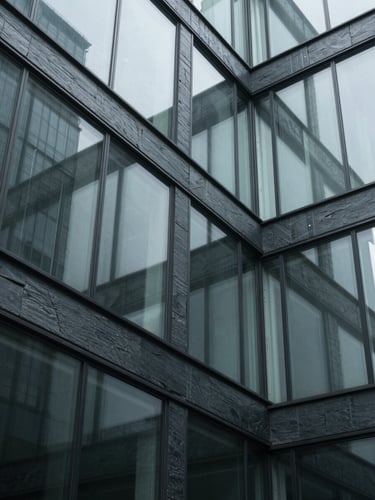 A tight, abstract architectural crop of glass and steel panels reflecting cool diffused daylight, sharp contrast shadows, 35mm