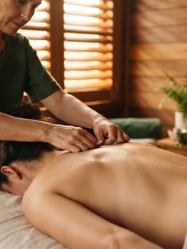 Close-up of master therapist's hands applying precise acupressure on a guest's back, soft golden-hour window light filtering through teak wooden shutters, 35mm