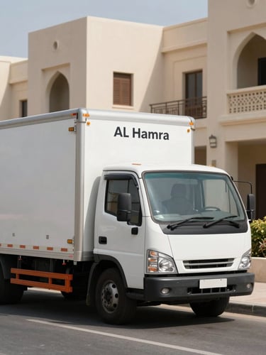 A clean, branded Al Hamra moving truck parked on a sun-drenched residential street in Ras Al Khaimah, natural UAE daylight, sharp architectural details in background.