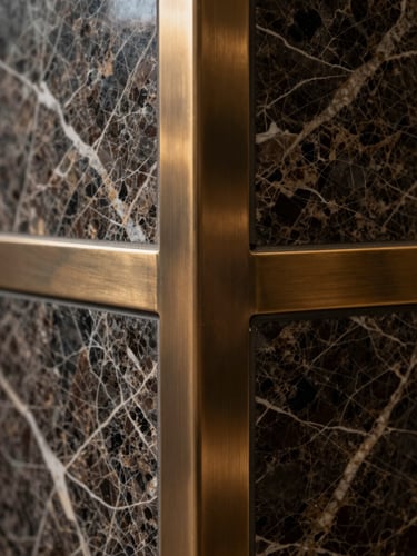 Close-up of premium architectural materials, dark veined marble meeting brushed bronze metal joints, dramatic natural side-light highlighting the textures.