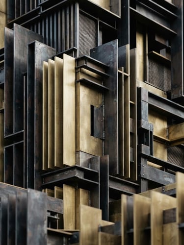 Macro detail shot of dense architectural isolation compound, brushed brass and steel layers, soft north-facing daylight, clean geometric shadows, architectural photography