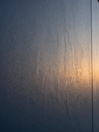 Macro detail of flawless textured paint finish on a modern wall, soft natural side lighting highlighting the precise texture, architectural-grade finish