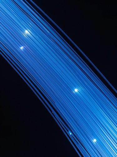 Macro shot of glowing blue fiber optic strands against a dark background, sharp focus, high contrast studio lighting with cool daylight accents.