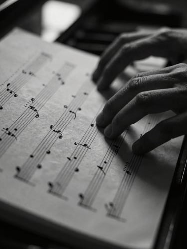 Macro close-up of tactile sheet music on textured paper, hands playing piano in deep shadow, soft directional window light, high-contrast monochrome tones.