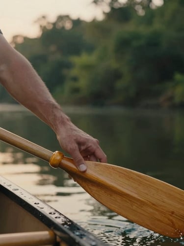 Close-up of a hand gently touching a wooden canoe paddle, soft golden hour light, blurred serene river in the background, atmospheric outdoor photography, 35mm.