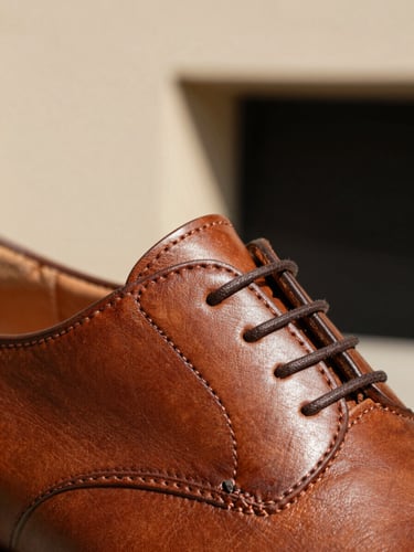 Macro close-up of premium brown leather shoe stitching, warm natural sunlight highlighting the rich texture, minimalist architectural background