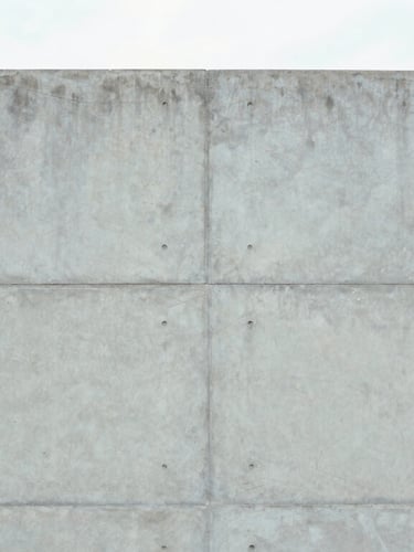 Close-up of a smooth architectural concrete wall with geometric formwork lines, soft overcast natural light, desaturated cool tones, symmetrical composition, 35mm