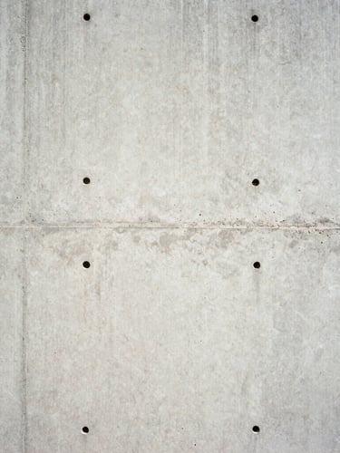 Close-up of a freshly poured concrete wall, high-contrast, harsh direct sunlight, sharp focus, architectural film photography, 35mm lens.