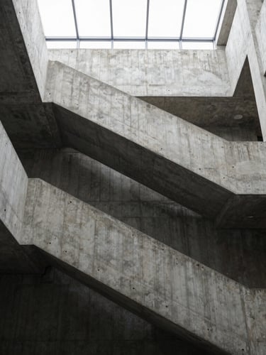 Tall, narrow portrait shot of a brutalist concrete stairwell, strong graphic lines, natural light from a high window, precise two-point perspective, empty.