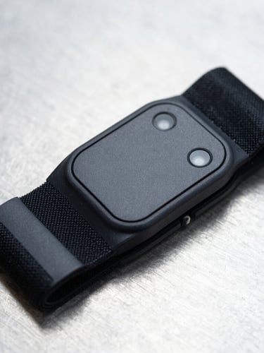 A high-performance heart rate strap resting on a clean metallic testing surface, showing the precise sensor connection snaps, crisp industrial lighting, cool tones