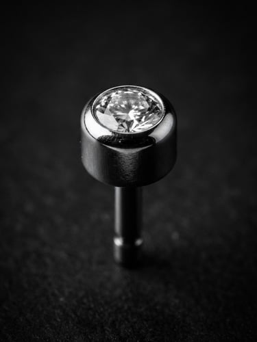 Extreme macro photography of a polished titanium threadless end, high-contrast black and white, sharp directional studio light, deep reflections, floating 3D depth, 85mm