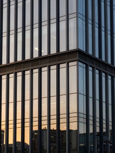 An architectural landmark building with a modern glass facade reflecting the warm golden hour sky, clean lines, high-end corporate editorial aesthetic.