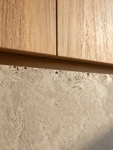 Detailed macro shot of raw concrete texture meeting warm noble wood and a subtle brushed bronze accent, warm sunlight, 35mm lens