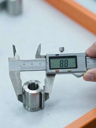 Close-up action shot of quality inspection, a hand using a digital caliper to measure a manufactured metal component, bright cool industrial lighting
