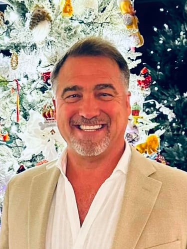 Smiling man in a tan blazer.