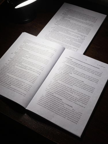 Close overhead shot of script pages spread on a dark studio desk under a precise cool strobe light, text columns visible with pencil annotations, one page turned at the corner, deep shadows framing the edges