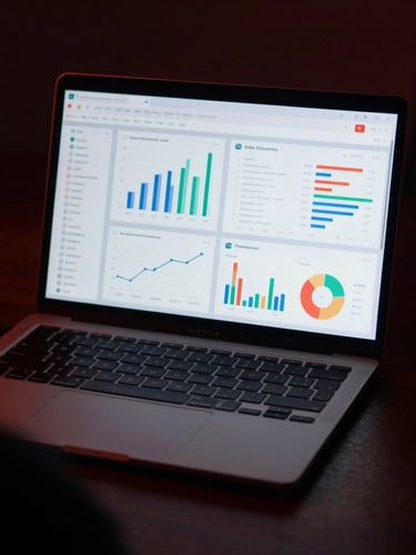 Over-the-shoulder shot of a modern laptop displaying clean analytics dashboards in moody, low-key lighting with a subtle crimson ambient glow, anamorphic lens, 35mm look