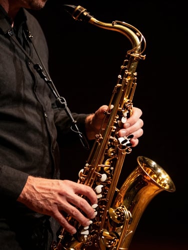 Gros plan intime des mains de Stéphane Nerplat sur un saxophone doré brillant, lumière latérale douce, fond noir, shallow depth of field