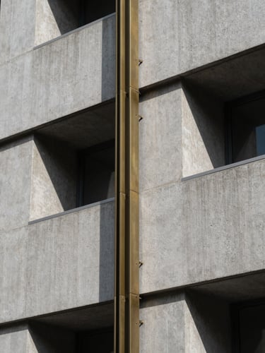 Extreme macro detail of a modern architectural facade, sharp shadows, cool daylight, concrete and brass elements.