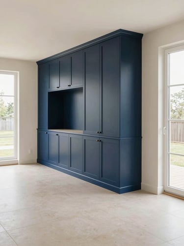 Wide interior shot of a freshly renovated living room, warm off-white walls, built-in navy cabinetry along one wall, clean tile flooring, soft north-facing daylight through tall windows, sharp detail on cabinet edges and grout lines, no people