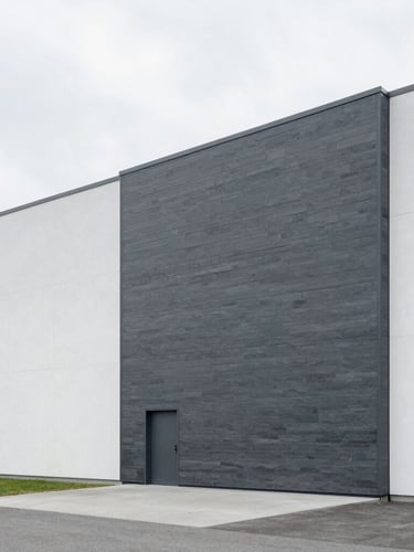 Wide architectural photography of a modern minimalist distribution center facade in Geneva, bright overcast daylight, cool slate and white tones, sharp focus, 35mm