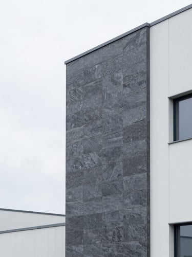 Clean architectural photography of a modern European distribution center facade, bright overcast daylight, cool slate and white tones, sharp focus, 35mm