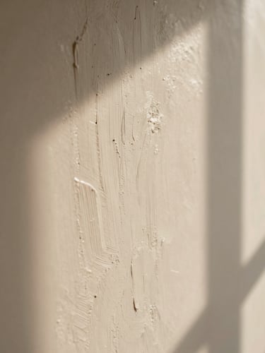 Close-up of a hand-troweled limewash wall, showing subtle texture and natural light creating soft architectural shadows, warm editorial photography, shallow depth of field