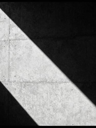 stark editorial fashion photography of a brutalist concrete wall casting sharp geometric shadows, high-contrast monochrome, 35mm film