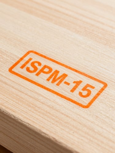 Flat-lay close-up of a crisp, clear ISPM-15 heat-treatment stamp on clean, raw timber, bright industrial daylight, sharp details.