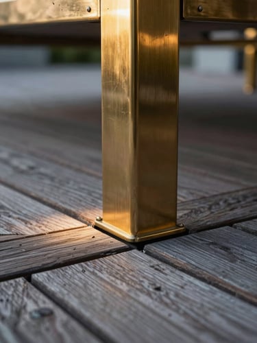 Close-up macro shot of weathered teak decking meeting a polished brass structural joint on a luxury terrace, dramatic architectural uplighting at dusk, shallow depth of field.