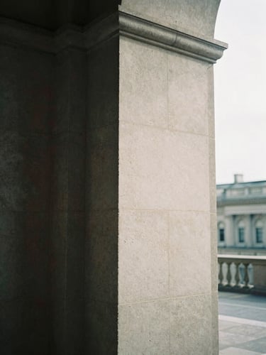 A close-up of a brutalist stone column with deep shadows, soft overcast daylight, architectural editorial photography, 35mm film