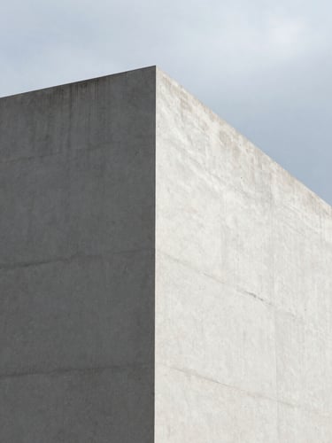 A minimalist close-up of a sharp architectural concrete corner with clean shadows under overcast daylight, modern corporate aesthetic.