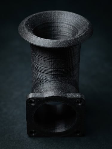 Sleek product photography of a 3D-printed motorsport velocity stack, high-contrast studio lighting, dark moody background, macro lens showing precise additive layers, 35mm