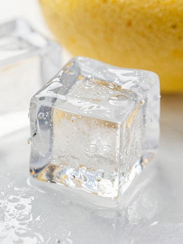 Macro close-up of a crystal-clear ice cube sweating with condensation droplets under high-key summer sunlight.