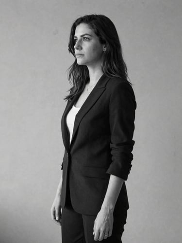 Retrato profesional en blanco y negro de una arquitecta en un estudio minimalista, iluminación natural suave de perfil, fondo de concreto limpio.