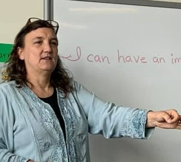 Leah Kyaio in front of a white board that reads "I an have an impact."