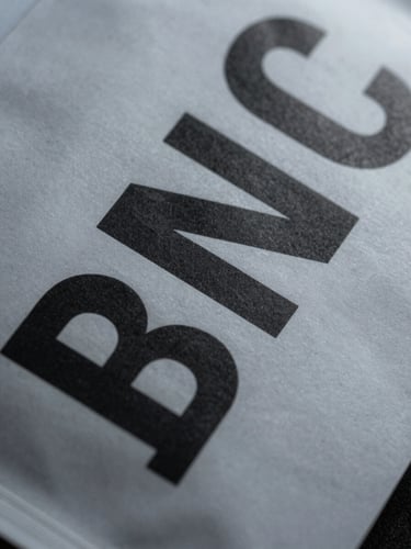 Extreme close-up of crisp typography on a physical packaging prototype, flat studio lighting, sharp high-contrast shadows, cool graphite tones.