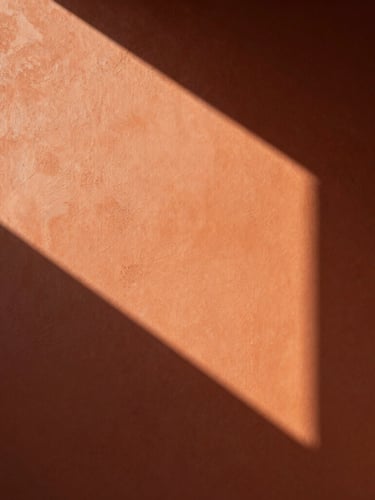 Close-up of premium warm terracotta wall texture, soft morning light casting geometric shadows, minimal luxury atmosphere, architectural detail, 35mm photography