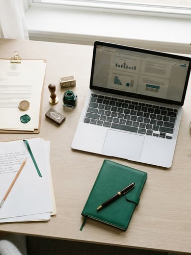 Overhead flat-lay of organized academic documents, legal stamps, and a clean laptop on a bright white desk, natural daylight, emerald green accents, sharp focus, 35mm