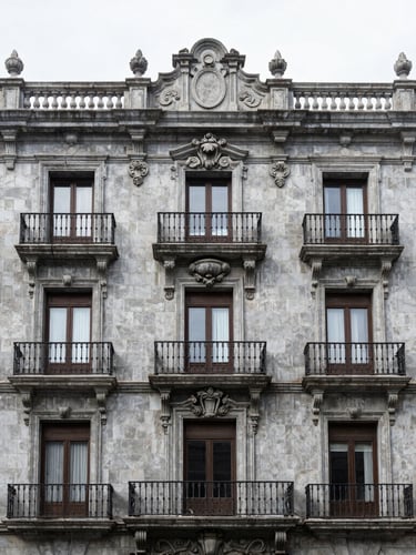 Symmetrical architectural elevation of a restored Porfirian building facade in Colonia Juárez, grey stone detailing, iron balconies, clean overcast daylight, 35mm