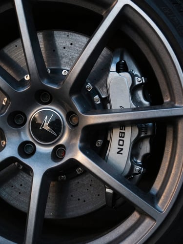 Tight detail crop of a high-performance sports car wheel and brake caliper, dramatic low-key lighting, sharp metallic reflections, 35mm lens.