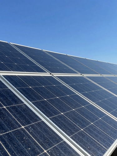 A close-up architectural shot of sleek monocrystalline solar panels reflecting a clear blue sky, bright direct sunlight, sharp high-contrast details